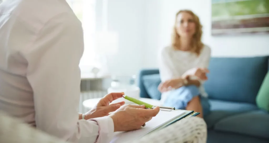 Therapist holds pencil and notepad with patient speaking in the background